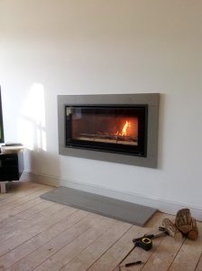 Grey granite contemporary surround and hearth, crafted by Millstone Designs and fitted with a wood burning stove