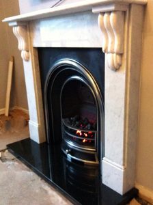 A traditional gas fireplace and surround, fitted with a boxed and lipped granite hearth crafted by Millstone Designs